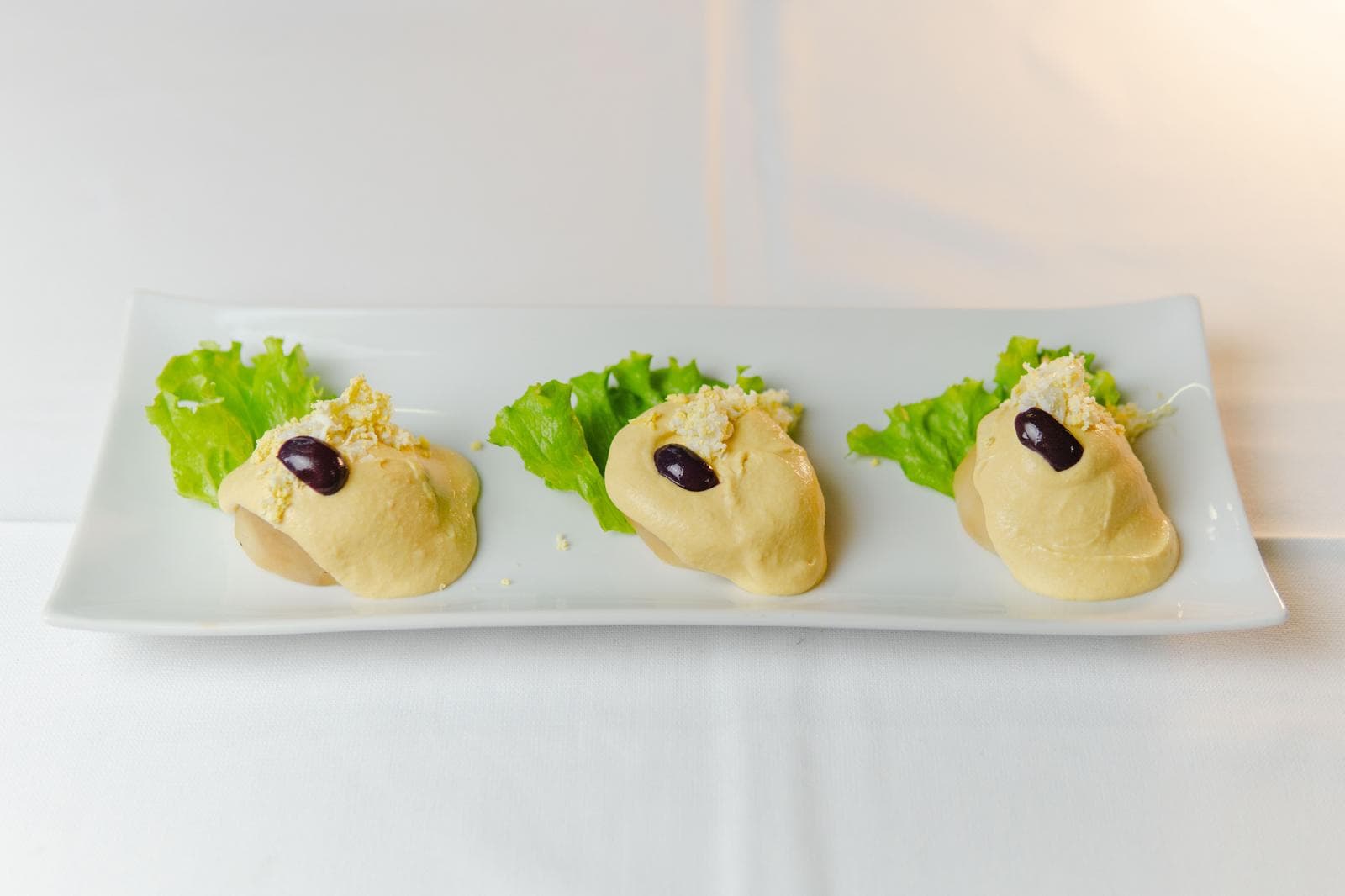 Papa a la huancaína with olives and lettuce